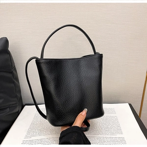 Close-up of black bucket bag showing premium lychee texture leather and top handle