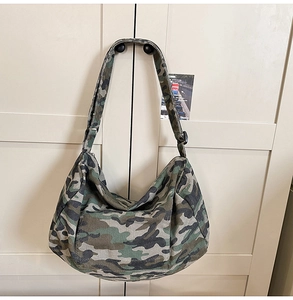 Detail of a large camouflage canvas crossbody bag hanging on a minimalist handle