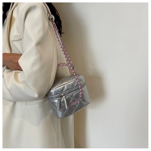 Close-up of silver quilted box bag with pink lettering and chain strap on white blazer