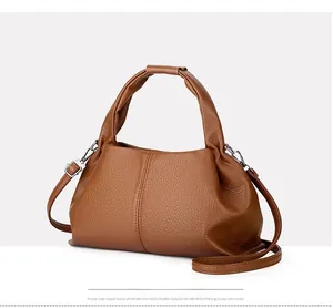 Macro detail of brown leather dumpling bag showing lychee grain texture and silver hardware
