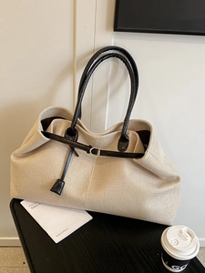 Large beige woven tote bag with black leather handles and silver metal hardware details