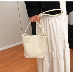 Detail of white litchi pattern leather bucket bag with creative knotted braided shoulder strap