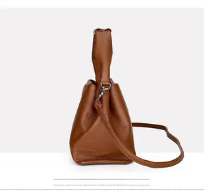 Close-up of brown lychee pattern leather shoulder bag with metallic buckle detail