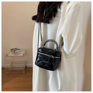 Close-up of black quilted box bag with silver chain strap and metal zipper detail