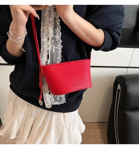 Detail of red bucket bag featuring lychee texture leather and silver knot pendant