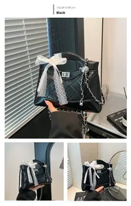 Detail of black quilted leather bucket bag with lace bow and silver chain strap