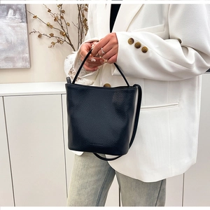Detail view of the black lychee pattern leather bucket bag held by a professional model