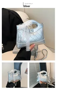 Close-up of silver quilted bucket bag featuring a lace bow and metal chain strap