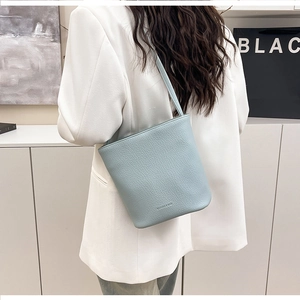 Close-up of light blue lychee pattern leather bucket bag with delicate gold lettering