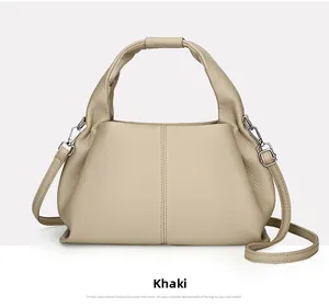 Detail of khaki leather cloud bag showing textured grain and silver metal hook strap
