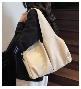 Detailed shot of crinkled cream tote bag with side pocket and wide shoulder strap