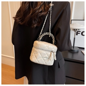 Detail of white quilted chain box bag showing the woven handle and dual zippers