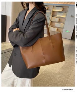 Caramel leather tote bag detail with fine stitching worn by model in a chic setting