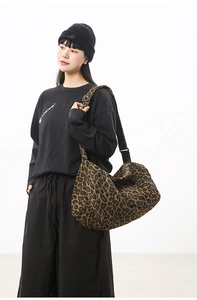 Model wearing a large leopard print canvas crossbody bag with adjustable shoulder strap