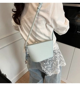 Detail of light blue bucket bag with lychee texture and cute silver dog charm