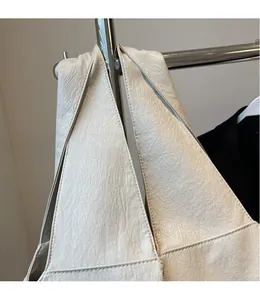Detailed close-up of cream leather shoulder bag with natural texture on a metal hanger