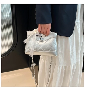 Close-up of silver quilted crossbody bag with lace bow detail and chain strap