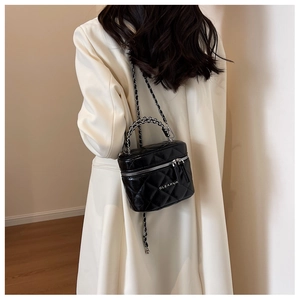Quilted black box bag with silver chain strap shown worn over a white coat