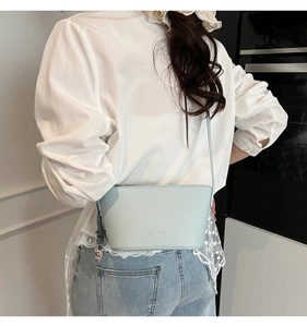 Detailed back view of a light blue lychee pattern leather bucket bag on a model