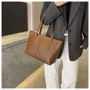 Brown leather tote bag featuring vertical stitching and large capacity for daily commuting