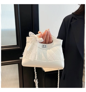 Close-up of quilted white handbag featuring a lace bow, silver chain, and twist lock