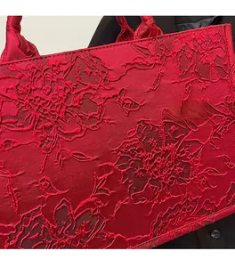 Close-up of deep red tote bag featuring intricate rose flower jacquard fabric texture