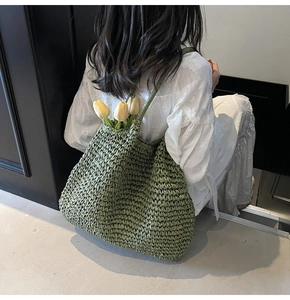 Close-up of green woven tote bag featuring textured straw material and delicate handles