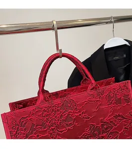 Detailed view of red tote bag with intricate floral 3D embroidery and sturdy handles