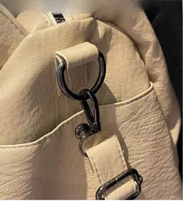 Close-up of gunmetal hardware hook and litchi texture on off-white crossbody bag