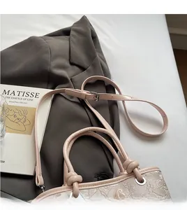 Détail du sac seau en dentelle rose clair avec poignée nouée et bandoulière réglable