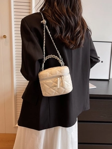 Elegant white quilted vanity bag with silver chain strap and top handle in a lifestyle setting