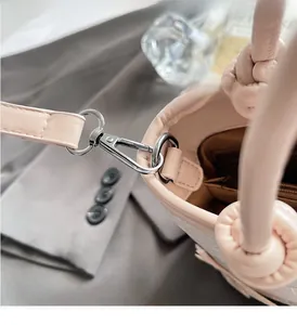 Détail du sac à main en cuir rose avec poignée nouée, ferrures argentées et poche zippée