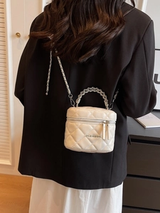 Elegant white quilted crossbody bag with silver chain strap shown on a black blazer
