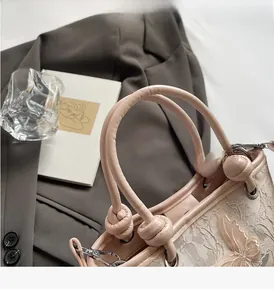 Gros plan d'un sac seau rose avec broderie papillon 3D et poignée en cuir nouée