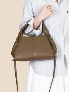 Brown lychee leather cloud dumpling bag with top handle and shoulder strap shown by model