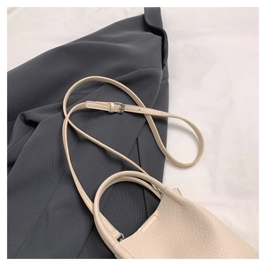 Close-up of beige lychee grain leather bucket bag with adjustable shoulder strap and dual handles