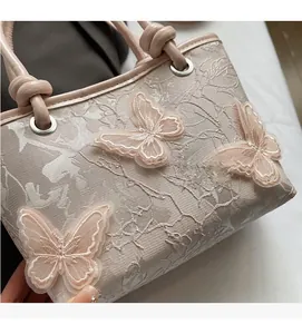 Détail d'un sac seau en dentelle florale avec broderie papillon 3D et poignée tressée