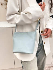 Minimalist light blue leather bucket bag styled with a white blazer for a chic work look