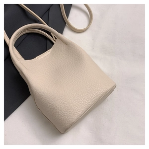 Macro detail of creamy white bucket bag featuring premium lychee grain faux leather texture