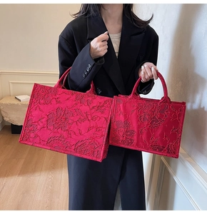 Detailed macro view of embossed red floral jacquard embroidery on luxury tote bridal bags