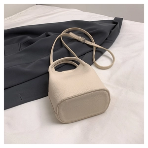 Detail of cream-white lychee texture bucket bag with handle and crossbody strap