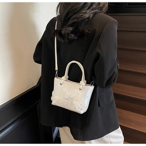Détail du sac seau en dentelle blanche avec appliques papillons 3D et fine bandoulière
