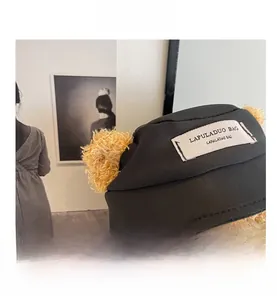 Close-up of black fabric bag featuring cute plush bear head and branded textile label