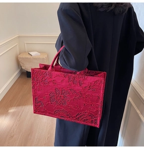 Detail of red bridal tote bag featuring 3D floral texture against a black wool coat