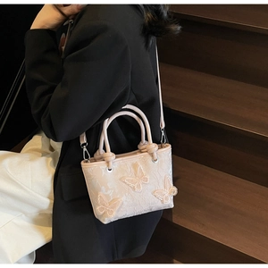 Détail du sac seau rose clair avec broderie papillon 3D et texture en dentelle