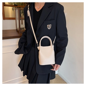 Close-up of cream lychee texture leather bucket bag with top handle and slim shoulder strap