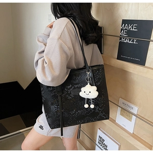 Detail of snake skin texture on black tote bag with white cloud plush charm accessory
