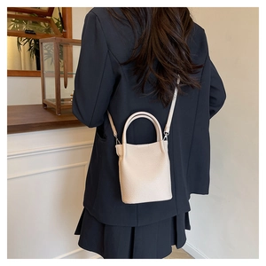 Close-up of beige lychee texture bucket bag with adjustable strap on a female model