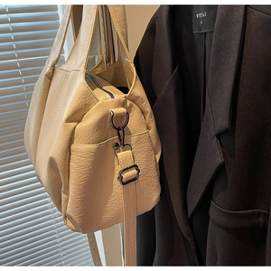 Detail of off-white large tote bag with soft leather texture and gunmetal zippers