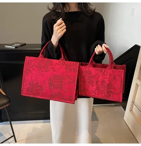 Macro view of red floral embroidery on luxury tote bags in two different sizes